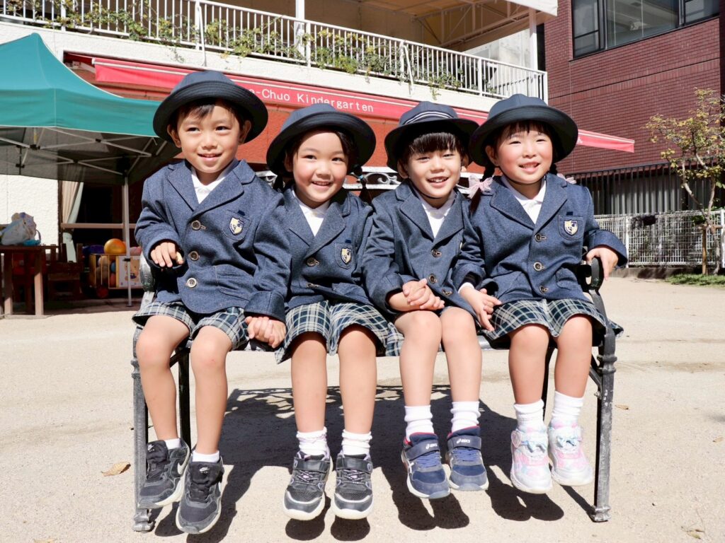 呉中央幼稚園の11月から4月の制服で呉中央幼稚園の男女の制服。紺色のブレザーに白いシャツ、チェック柄のボトムスを着た園児たち